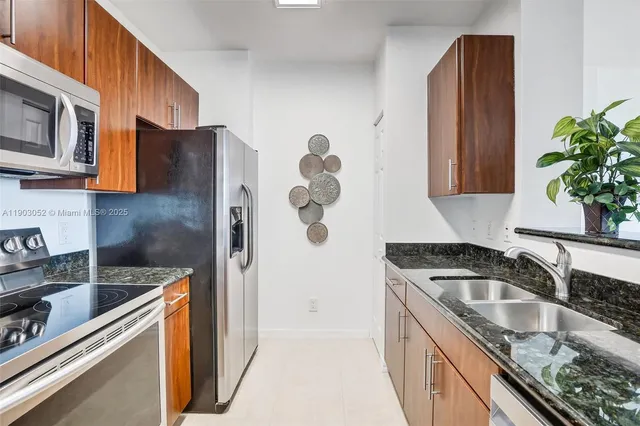 a kitchen with granite countertop a sink stove and refrigerator