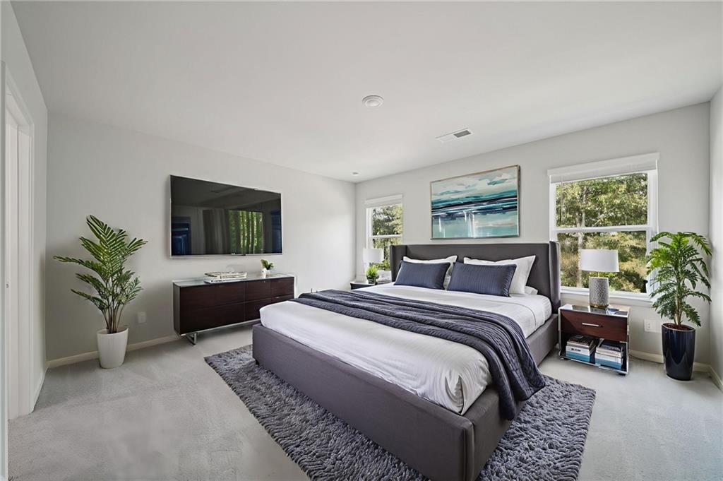 7830 Marie Way Fairburn, GA 30213 - Photo 17 of 30 a spacious bedroom with a bed a couch and a potted plant