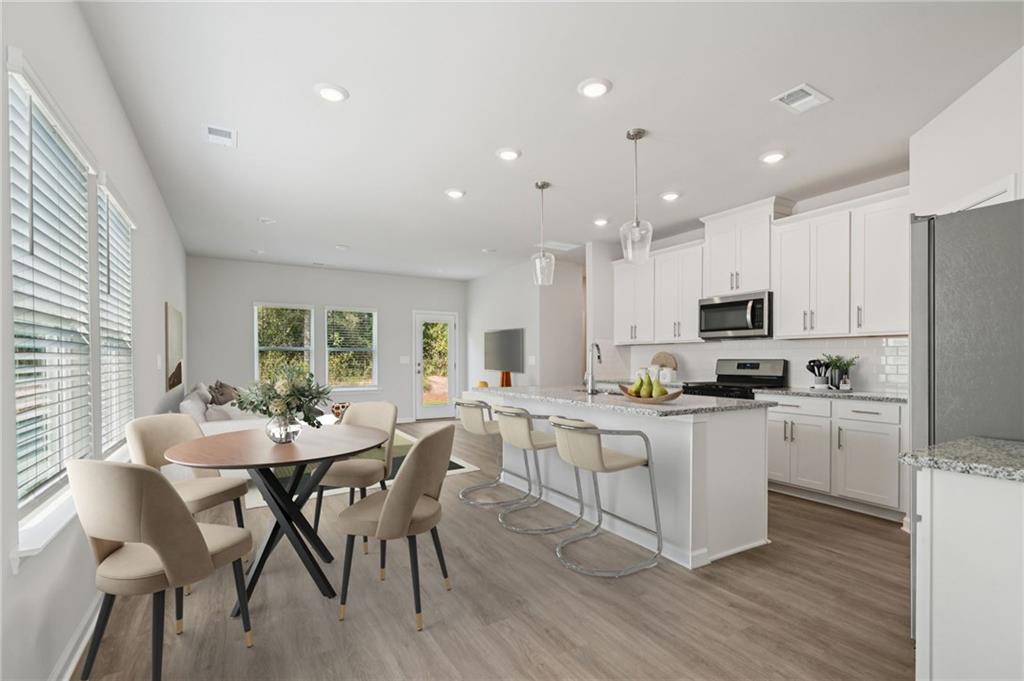 7830 Marie Way Fairburn, GA 30213 - Photo 7 of 30 a kitchen with stainless steel appliances kitchen island granite countertop a stove a sink a refrigerator dining table and chairs