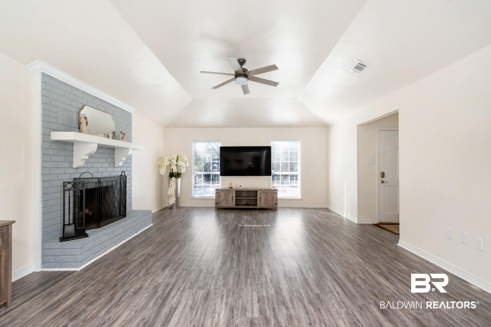 9410 Ashwood Court Mobile, AL 36695 - Photo 5 of 20 Unfurnished living room with dark wood-style floors, a ceiling fan, and a brick fireplace