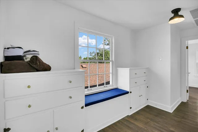 a view of an empty room with wooden floor fireplace and a window