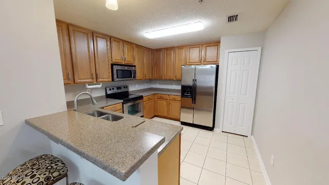 a kitchen with stainless steel appliances granite countertop a refrigerator a stove a sink a microwave and island
