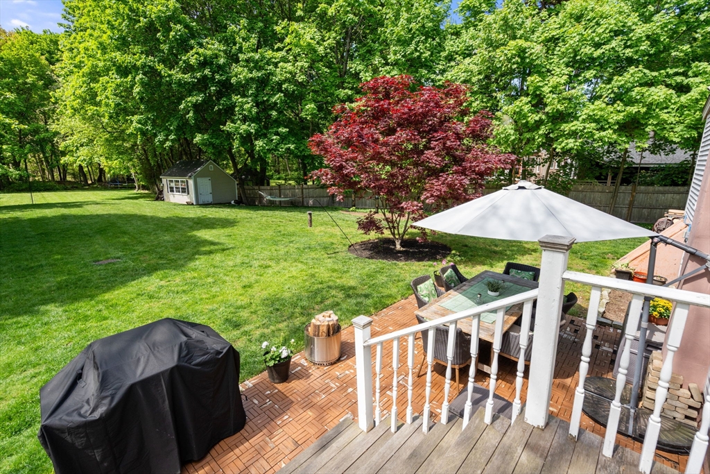 25 Fox Lane Concord, MA 01742 - Photo 16 of 24 a view of a wooden dinning table and chairs under an umbrella