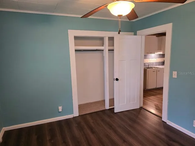 a view of an empty room with wooden floor and a ceiling fan