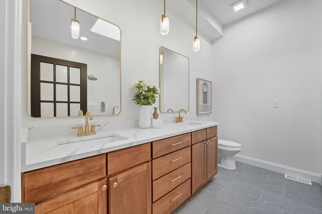 a bathroom with a double vanity sink a toilet and a mirror