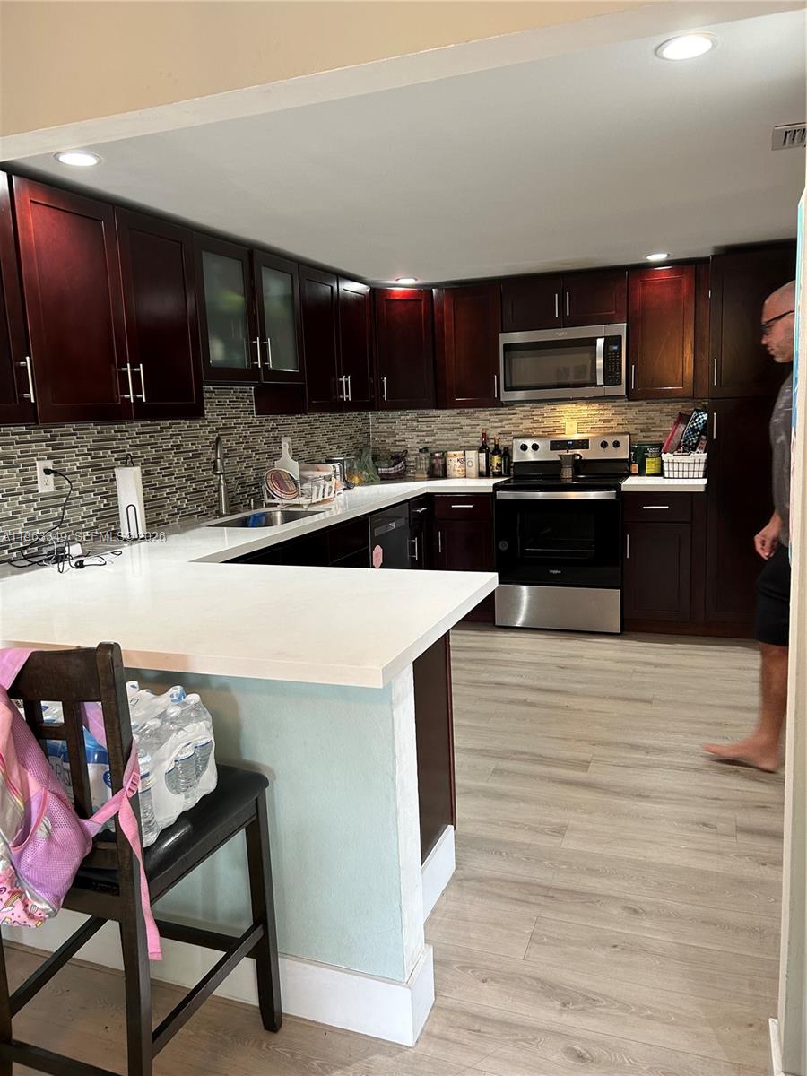 6619 Southwest 116th Place, Unit B7 Miami, FL 33173 - Photo 4 of 27 a kitchen with stainless steel appliances kitchen island granite countertop a stove a sink and a microwave