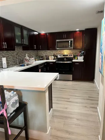 a kitchen with stainless steel appliances wooden cabinets granite counter tops and a view of living room