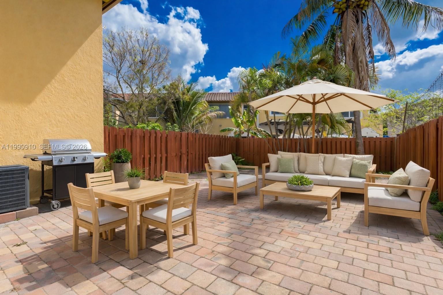4977 Southwest 135th Way Miramar, FL 33027 - Photo 3 of 28 a view of a patio with open dining table and chairs under an umbrella with a barbeque