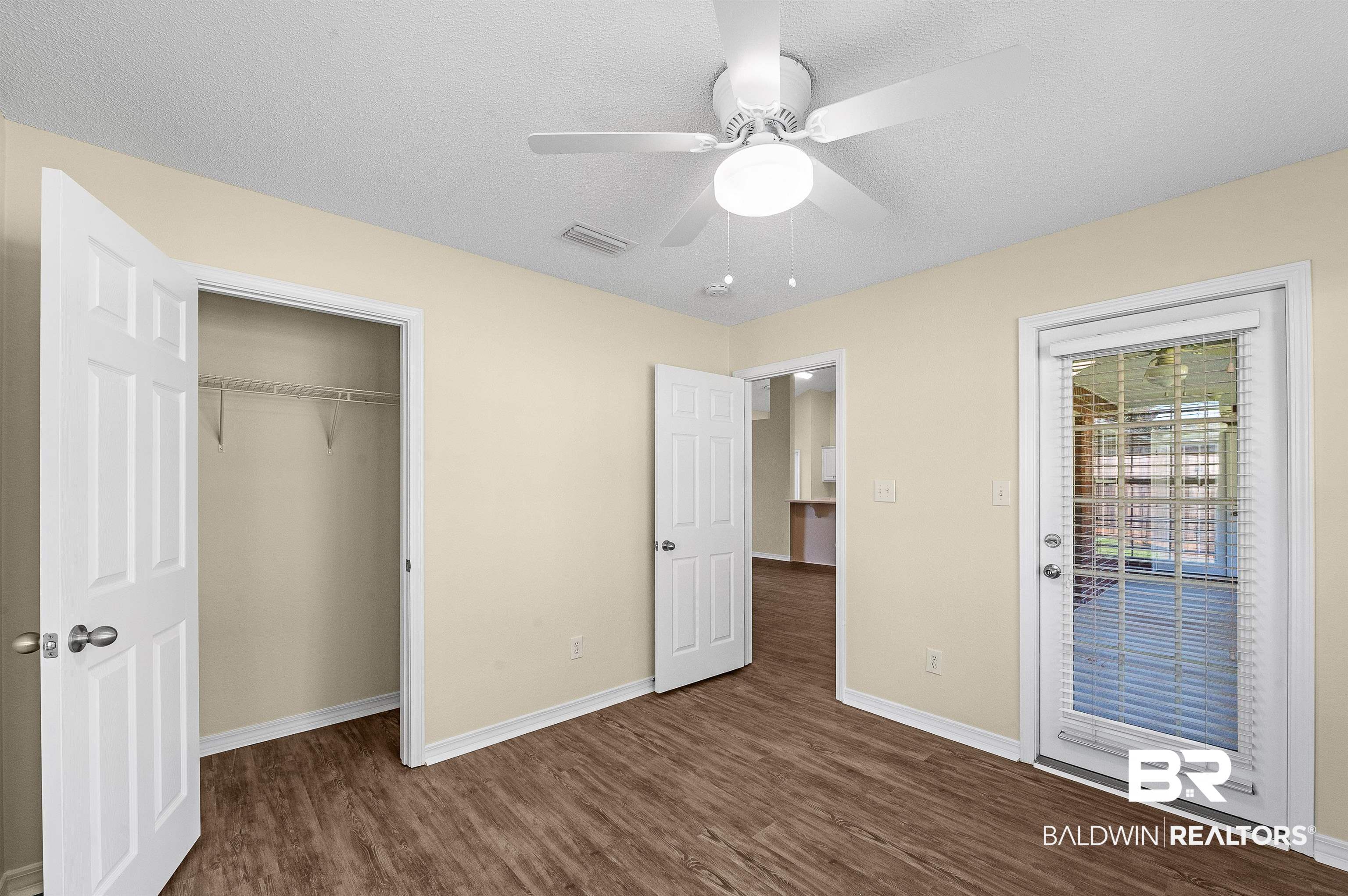 12443 Venice Boulevard Foley, AL 36535 - Photo 58 of 59 Unfurnished bedroom with a textured ceiling, access to outside, ceiling fan, a closet, and dark wood-type flooring