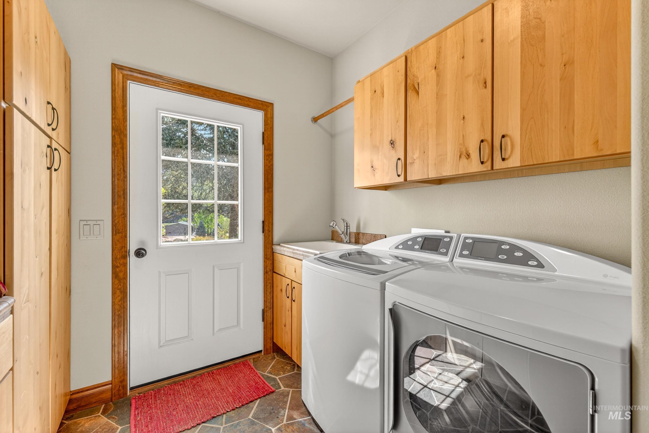 113 Deford Road White Bird, ID 83554 - Photo 25 of 49 Utility room featuring a white door with nine-pane glass, natural wood-finish cabinetry, a utility sink with a chrome faucet, and geometric tile flooring