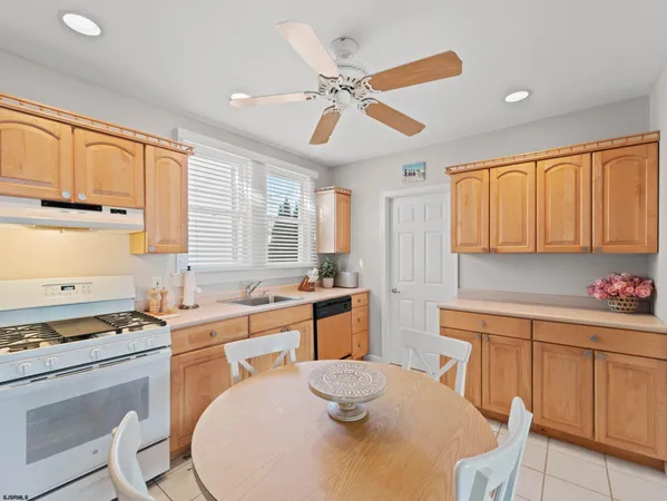 a open kitchen with stainless steel appliances granite countertop a stove top oven a sink a dining table and chairs with wooden floor