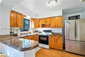 a kitchen with stainless steel appliances granite countertop a refrigerator a sink a stove and white cabinets with wooden floor