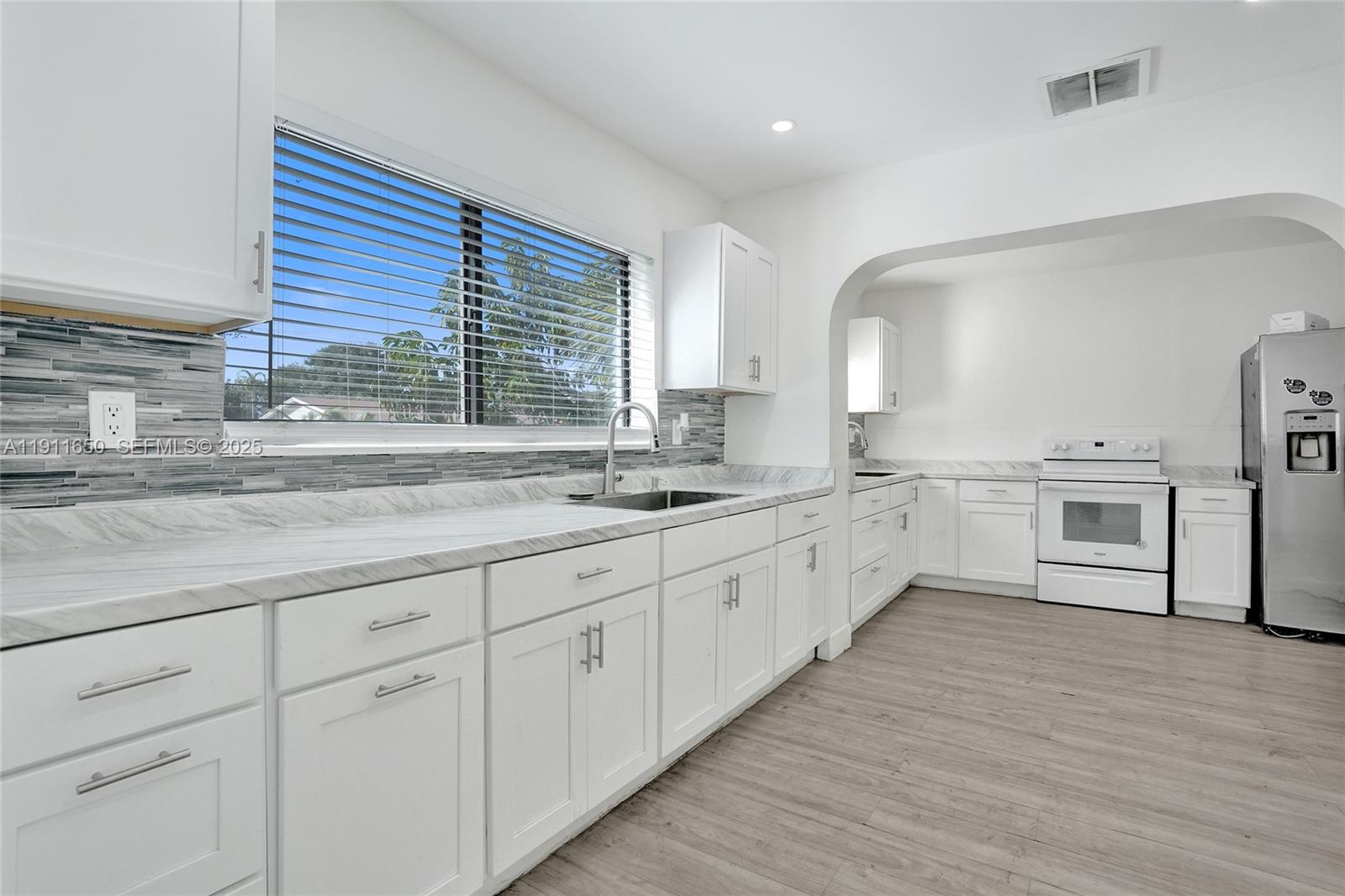 6470 McClellan Street Hollywood, FL 33024 - Photo 48 of 74 a large white kitchen with granite countertop a large window and white stainless steel appliances