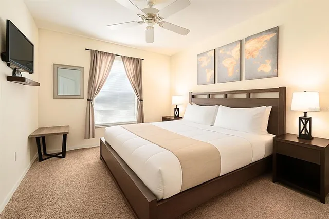 a bedroom with a bed and a flat tv screen on dresser