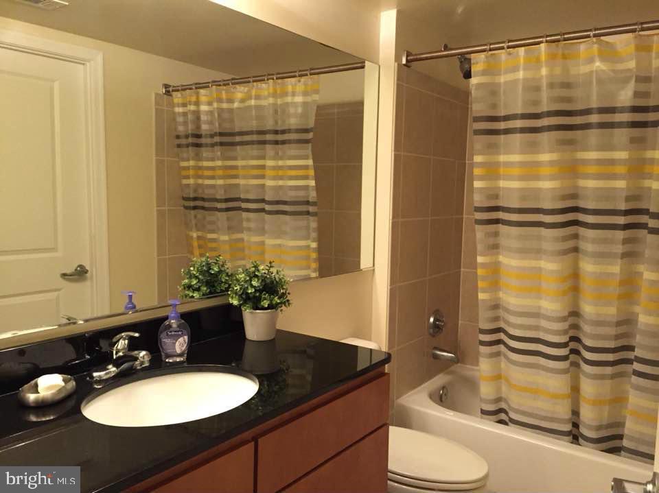 915 E Street Northwest, Unit 702 Washington, DC 20004 - Photo 8 of 10 a bathroom with a granite countertop sink toilet and shower