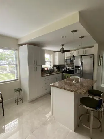 a kitchen with stainless steel appliances kitchen island granite countertop a table chairs sink and cabinets