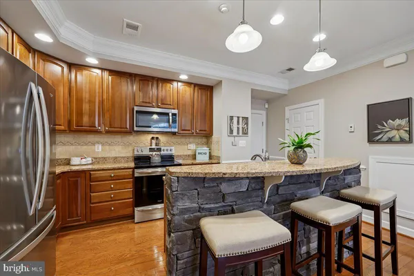 a kitchen with granite countertop a stove a sink dishwasher a dining table and chairs with wooden floor