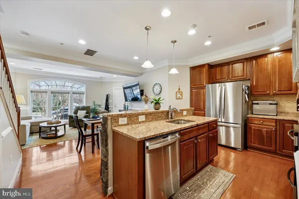 a kitchen with stainless steel appliances granite countertop a stove refrigerator a dining table and chairs with wooden floor