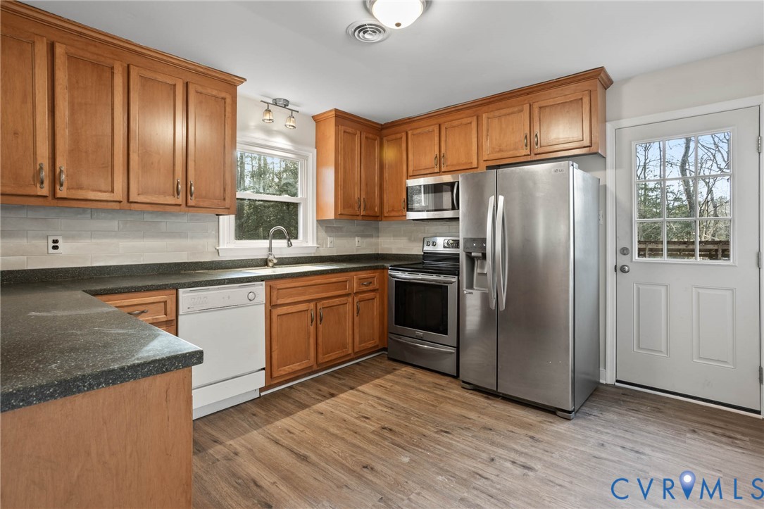 3843 Quinton Road Quinton, VA 23141 - Photo 11 of 26 a kitchen with stainless steel appliances granite countertop a refrigerator a sink dishwasher a stove with wooden cabinets and floor