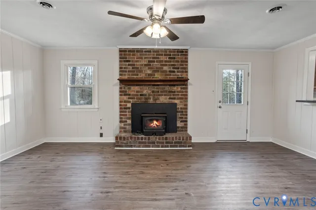 a view of an empty room with wooden floor fireplace and a window
