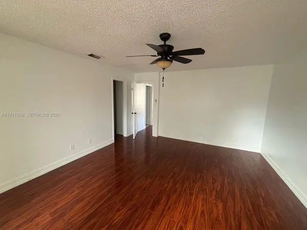 a view of a room with wooden floor and a ceiling fan