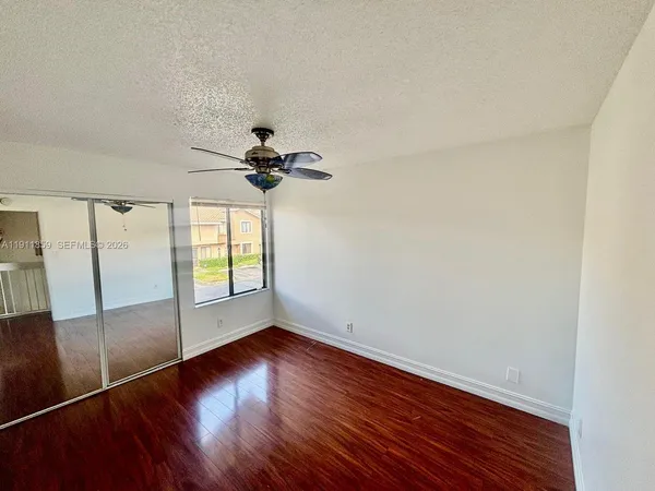 a view of empty room with wooden floor and fan