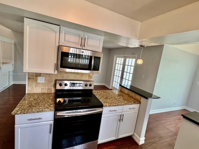 a kitchen with granite countertop cabinets stainless steel appliances and a counter space