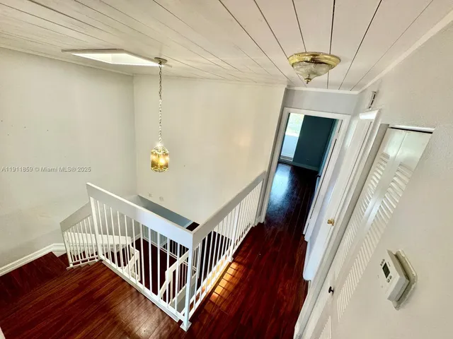 a view of staircase with lots of frames on wall and wooden floor