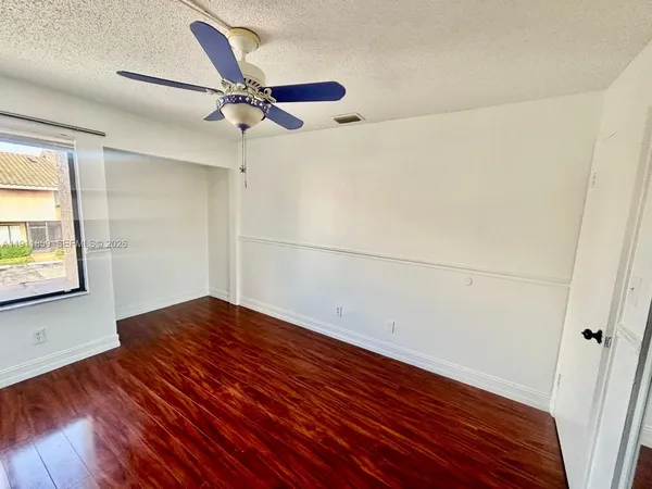 a view of empty room with wooden floor and fan