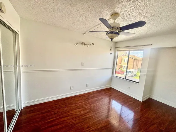 an empty room with wooden floor fan and windows