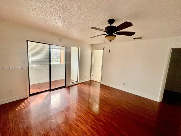 a view of empty room with wooden floor and fan