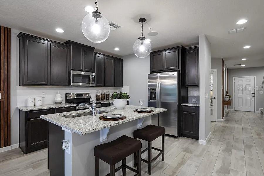 247 Smugglers Way Apopka, FL 32712 - Photo 4 of 5 a kitchen with stainless steel appliances kitchen island granite countertop a refrigerator a sink a stove a microwave and island