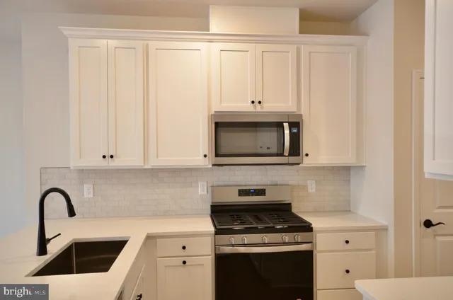 a kitchen with white cabinets a sink and appliances