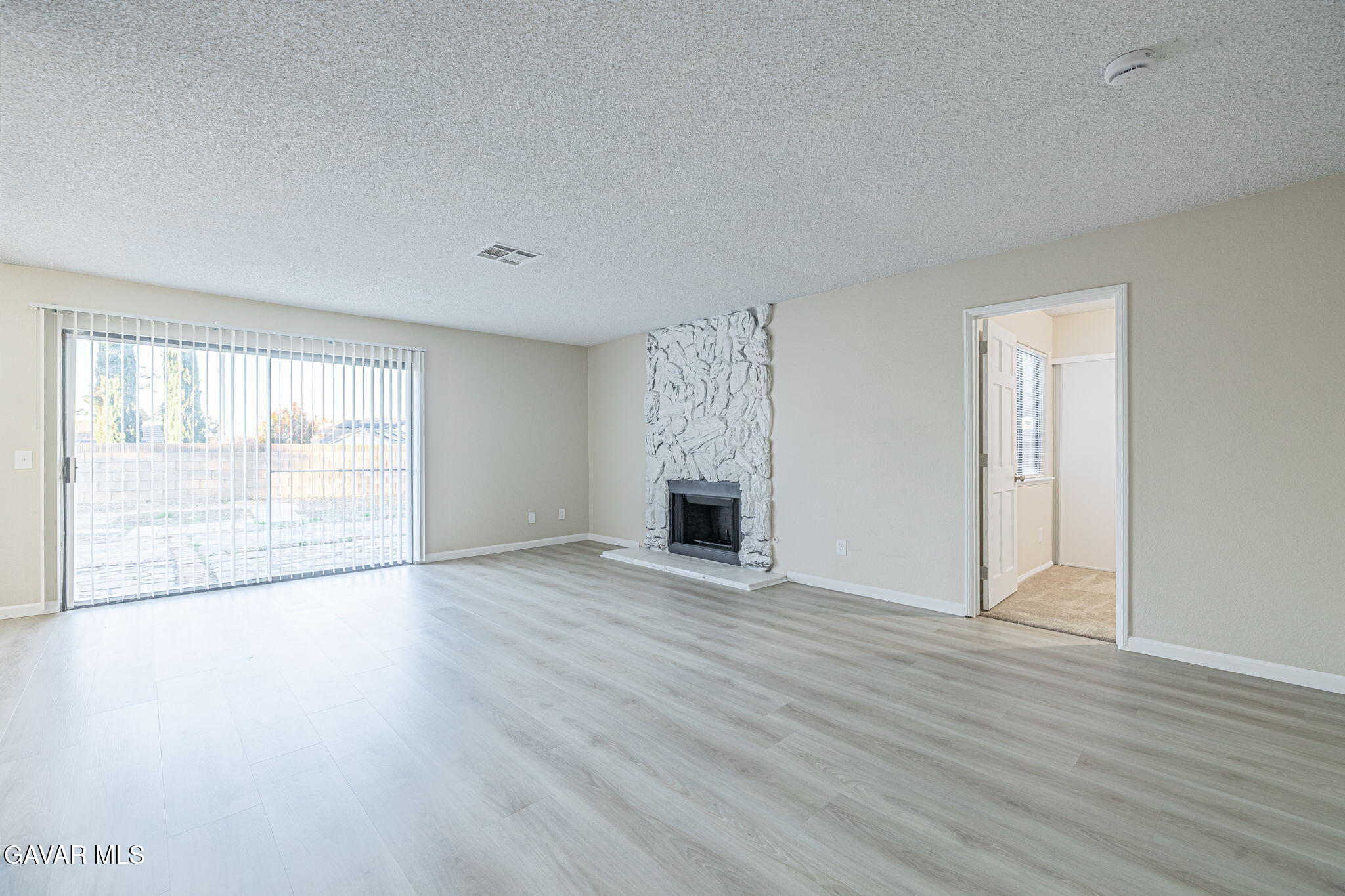 1201 Camran Avenue Lancaster, CA 93535 - Photo 23 of 49 an empty room with wooden floor fireplace and windows