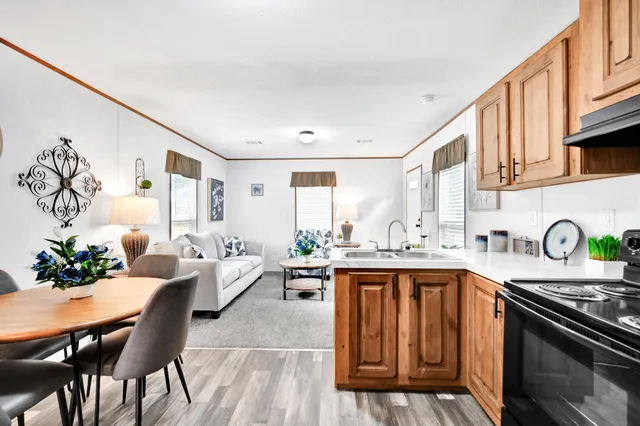 a kitchen with stainless steel appliances granite countertop a stove top oven a sink dishwasher and cabinets with wooden floor