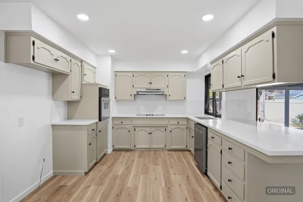 a kitchen with a sink a refrigerator and white cabinets