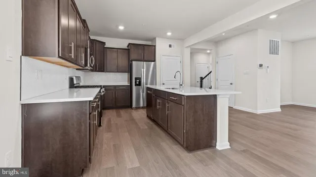 a kitchen with stainless steel appliances granite countertop a refrigerator a sink dishwasher a stove and a wooden floors