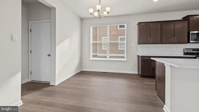 an empty room with wooden floor and a kitchen