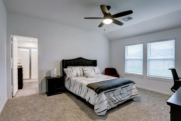 a bedroom with a bed next to a window with a chandelier