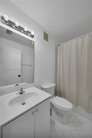a bathroom with a sink a toilet a mirror and shower curtain