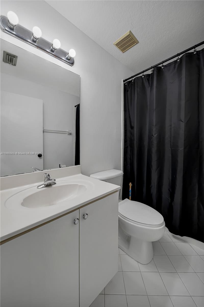 1261 Southeast 27th Street, Unit 203 Homestead, FL 33035 - Photo 16 of 18 a bathroom with a sink a toilet a mirror and shower curtain