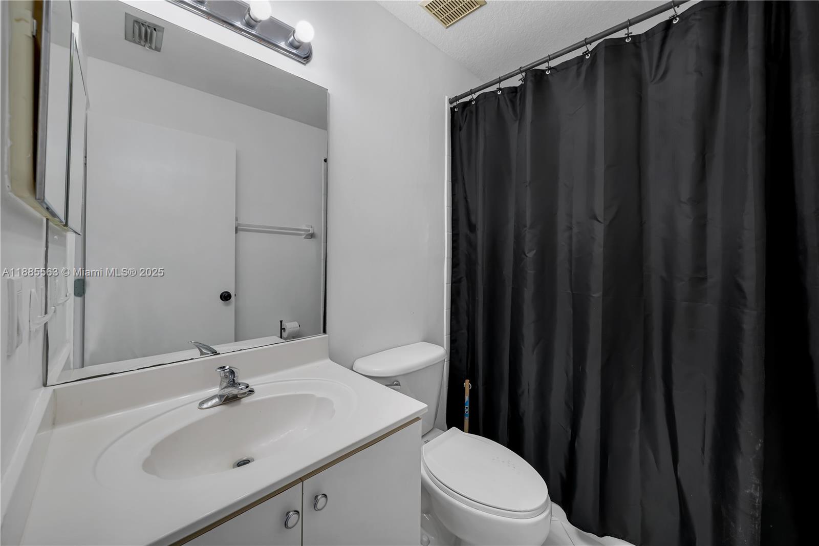 1261 Southeast 27th Street, Unit 203 Homestead, FL 33035 - Photo 18 of 18 a bathroom with a sink a toilet a mirror and shower curtain