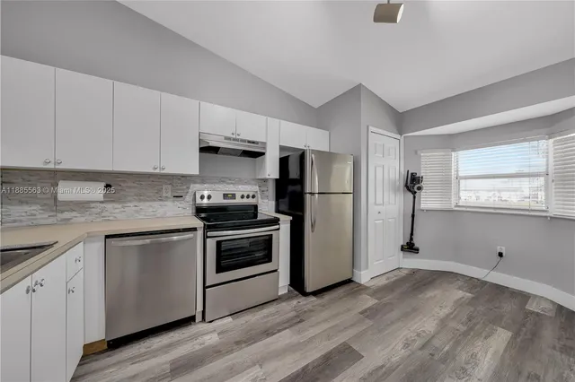 a kitchen with granite countertop a refrigerator stove and sink