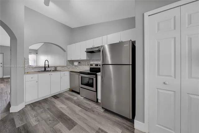 a kitchen with a refrigerator sink and cabinets