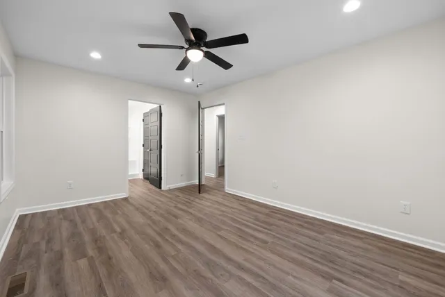 an empty room with wooden floor and ceiling fan