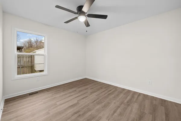 an empty room with a window and a ceiling fan