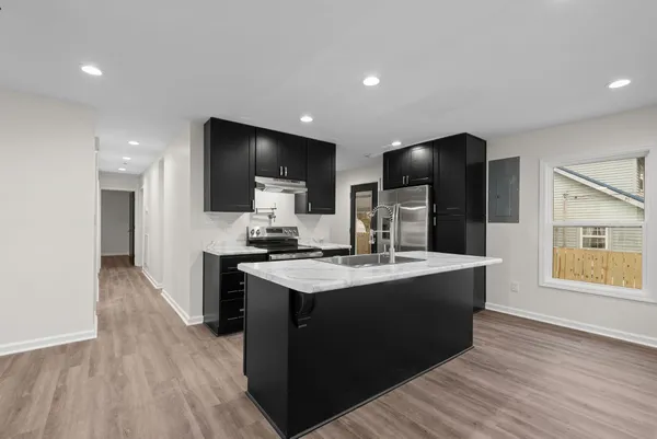 a kitchen with stainless steel appliances granite countertop a sink a stove and a wooden floors