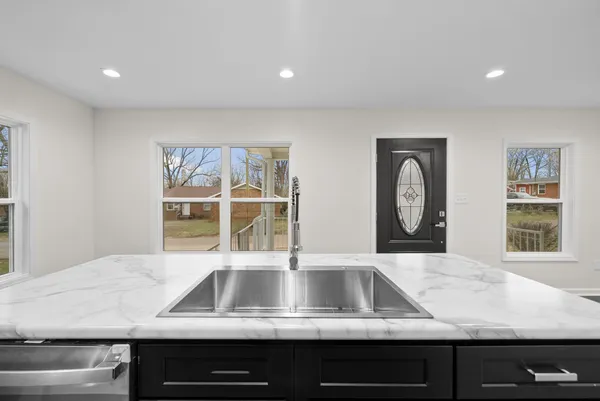 a view of kitchen sink with granite countertop window and cabinets