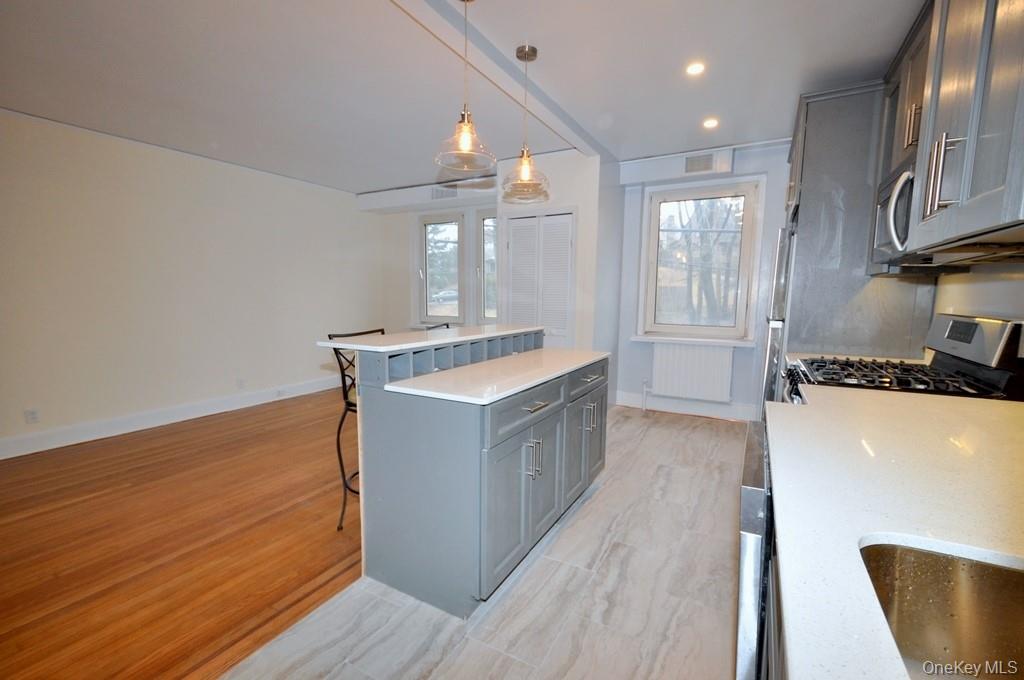 69 Harney Road, Unit 3A Scarsdale, NY 10583 - Photo 12 of 22 Renovated Kitchen with center Island, pendent lighting, Granite Counters, Stainless Steel Appliance including a dishwasher, range, microwave and refrigerator. The wall separating the eat-in-kitchen and living room have been removed and a center Island installed with electric and USB outlets installed to create an open concept.