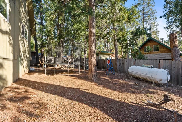 a view of a backyard with table and chairs and a large tree